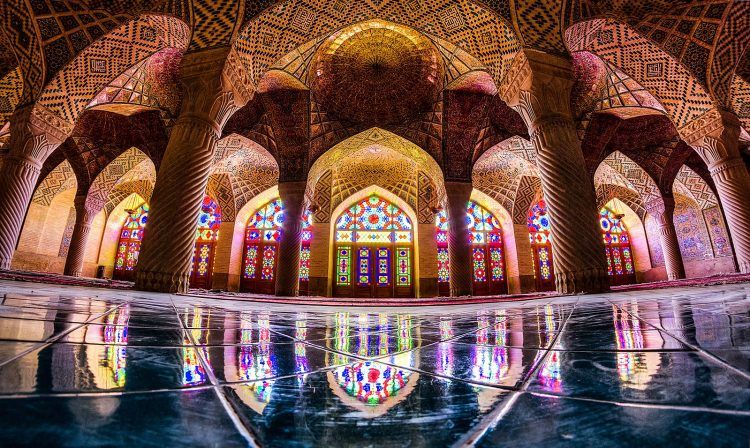 Picture of a stained-glass window from the floor of the mosque, also featured is the tiled ceilings and support collumns