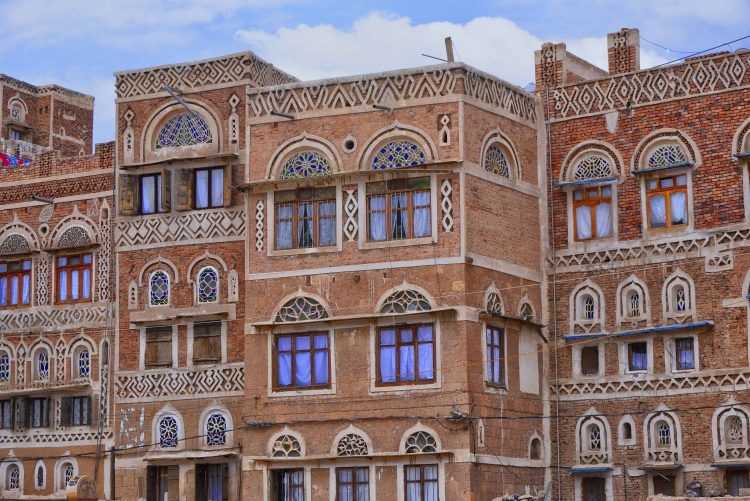 A view of buildings in Sana with half-circle stained-glass windows set above the functional windows.