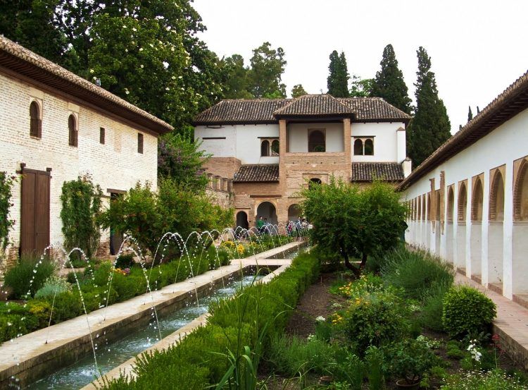 A long garden bisected by a long water feature, with buildings on all three sides.