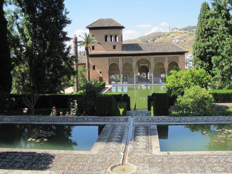 Large artificial pools of water surrounded by stone paths snd greenery. 