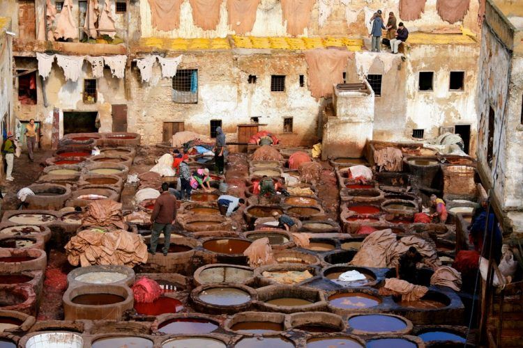 Pools of colored tanning liquid and leather hanging from surrounding buildings.