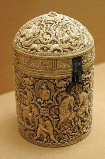 A cylindrical white ivory case with intricate drawings.