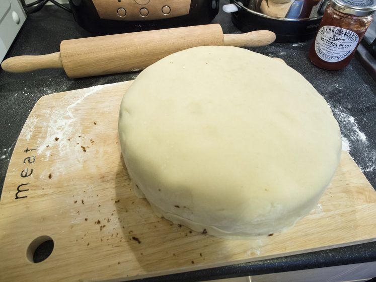 An undressed white cake on a cutting board.
