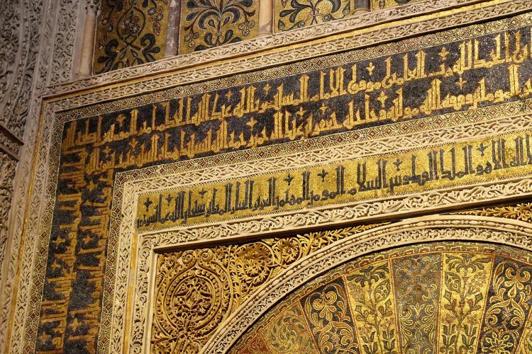 Ornate black and gold Arabic inscriptions on a corner of a wall.