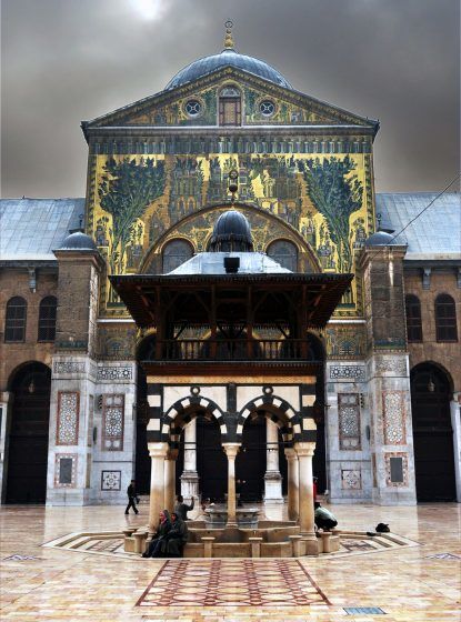 A picture of the entrance to the Great Umayyad Mosque of Damascus showing a painting of greenery and buildings.